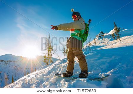 Freeride Snowboarder Stands On Hillside At Dawn And Shows His Ha