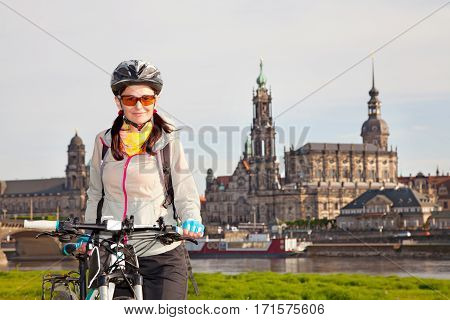 Adult attractive female cyclist posing against the background of 