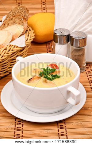 Puree soup of corn with mussels with parsley in a white plate