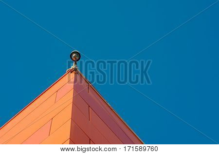 Security camera install corner outside of building against blue sky background.