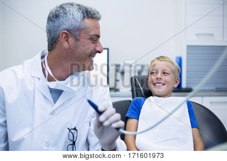 Smiling dentist talking to young patient in dental clinic
