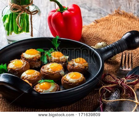 Mushrooms with quail eggs. Mushrooms on black pan. Quail eggs pepper paprika parsley and cutlery close. Selective focus