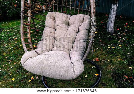 lonely hanging chair in the summer garden under a tree. apples lying on grass