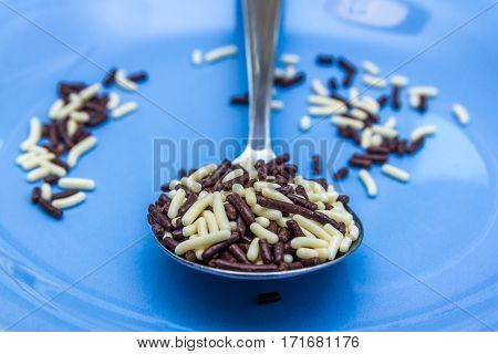 pure and white chocolate hagelslag sprinkles in spoon with blue background