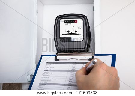Close-up Of A Technician Hand Writing Reading Of Meter On Clipboard