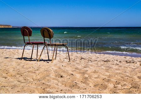 Two old chairs on the beach. Two is always better than one. Together, even in old age better. The invitation to sit and think about the past.