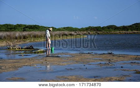 Mallacoota, Australia - Jan 5, 2017. Man collecting baits. Man standing in the water at the beach.