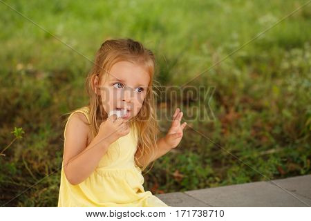 Nice little girl eating cotton candy. A walk in the summer park. Summer vacation. Outdoor Activities.