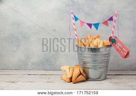Hamantaschen cookies or hamans ears in bucket over rustic background for Jewish holiday Purim concept