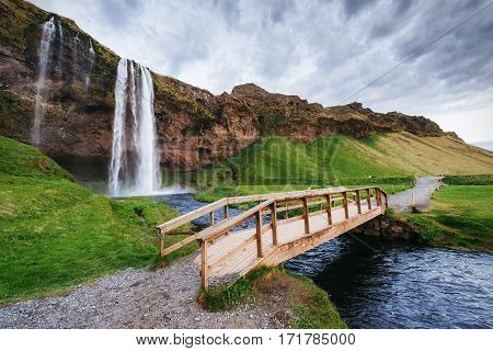 Seljalandfoss waterfall at sunset. Bridge over the river. Fantastic nature. Iceland. Europe