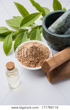 Chandan or sandalwood powder with traditional mortar, sandalwood sticks, perfume or oil and green leaves. selective focus