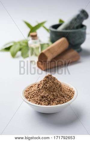 Chandan or sandalwood powder with traditional mortar, sandalwood sticks, perfume or oil and green leaves. selective focus