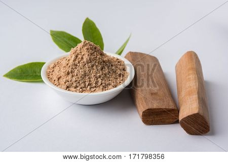 Chandan or sandalwood powder with traditional mortar, sandalwood sticks, perfume or oil and green leaves. selective focus