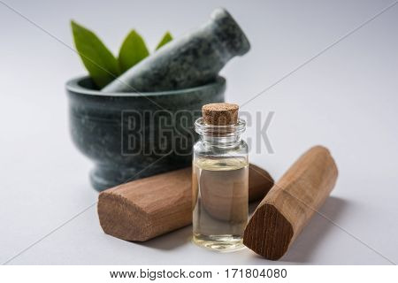 Chandan or sandalwood powder with traditional mortar, sandalwood sticks, perfume or oil and green leaves. selective focus