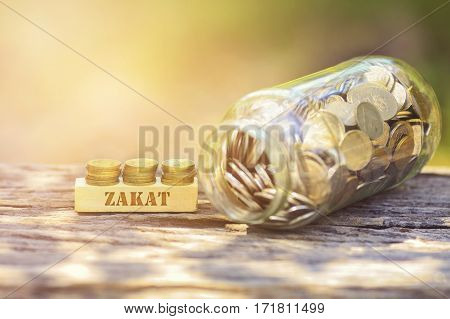 Zakat Word Golden Coin Stacked With Wooden Bar On Shallow Dof Green Background.