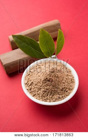Chandan or sandalwood powder with traditional mortar, sandalwood sticks, perfume or oil and green leaves. selective focus