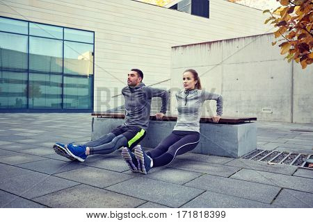 fitness, sport, training, people and lifestyle concept - couple doing triceps dip exercise on bench outdoors