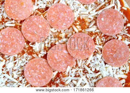 Raw unready pizza with sausage and cheese as background top view closeup
