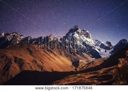 Fantastic starry sky. Autumn landscape and snow-capped peaks. Main Caucasian Ridge. Mountain View from Mount Ushba Meyer, Georgia. Europe