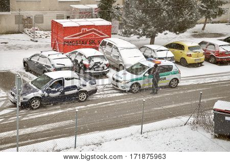 Bytca Slovakia - February 17 2017: Police traffic partol stop a car. Policeman stand outside vehicle in bad weather while snow falls.
