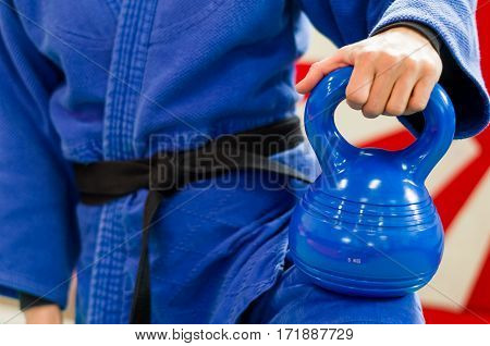 Close Up of Woman in Blue Judo Gi and Black Belt which is Train with weights and kettlebells Girya