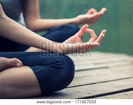 Close up hand. Woman do yoga outdoor. Woman exercising yoga at the nature background select focus