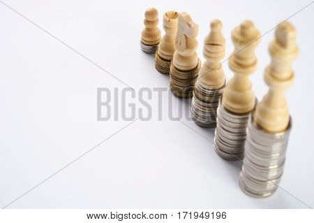 Growing coins stacks on white background. White chess figures standing on coins meaning power and career growth. Financial growth saving money business finance wealth and success concept.
