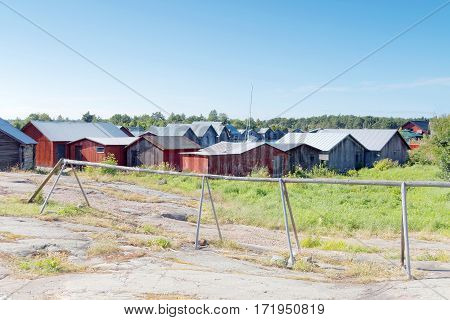 Many red and gray boathouses in the old fishing harbor in the archipelago in Aaland Finland