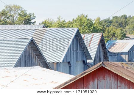 Roofs of corrugated iron on gray and red decayed boathouses in the archipelago in Aaland Finland