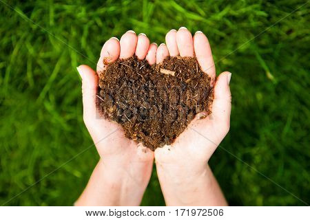 Hands Holding An Earth Heart On Natural Green Background. Ecology Concept