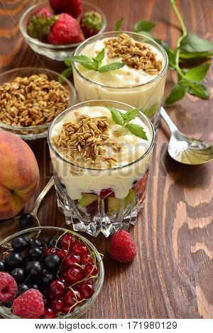Dessert with fresh berries granola and custard in glasses, vertical