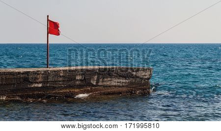 Pier With A Red Flag In The Sea