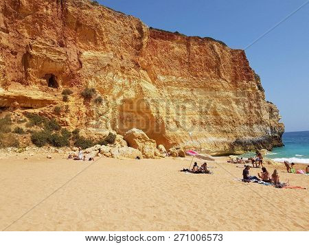 People Sunbathing On The Beach Beside Benagil Caves, Algarve, Portugal.