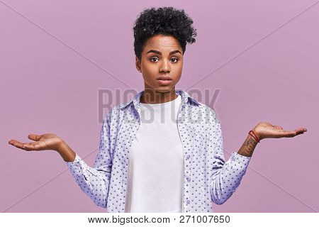 Hesitant Puzzled Young Female With Afro Haircut, Shrugs Shoulders And Faces Dilemma, Looks Clueless 