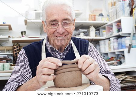 Senior Man Making Coil Pot In Pottery Studio