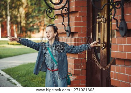 Young Cheerful Child Piddle Near Door Of Building From Red (brown) Brick Near Green Grass Outdoors. 