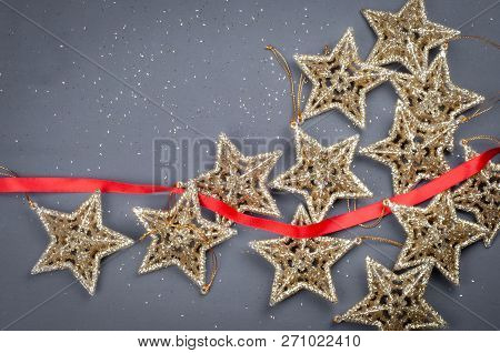 Golden Stars Christmas Composition Decorations On A Gray Background With Red Ribbon