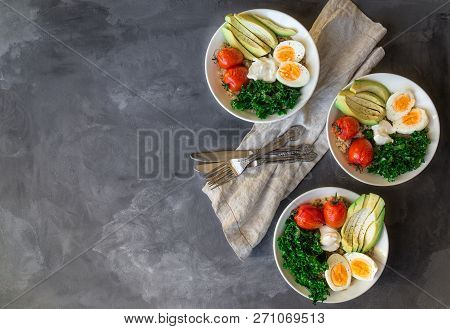 Quinoa Buddha Bowls With Baked Tomatoes, Avocado, Kale, Boiled Eggs And Greek Yogurt On Gray Concret