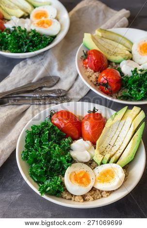 Quinoa Buddha Bowls With Baked Tomatoes, Avocado, Kale, Boiled Eggs And Greek Yogurt On Gray Concret