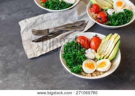 Quinoa Buddha Bowls With Baked Tomatoes, Avocado, Kale, Boiled Eggs And Greek Yogurt On Gray Concret