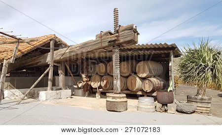 Big And Very Old Wine Press Beside A Pile Of Wine Barrels In Gran Canaria, Canary Islands.