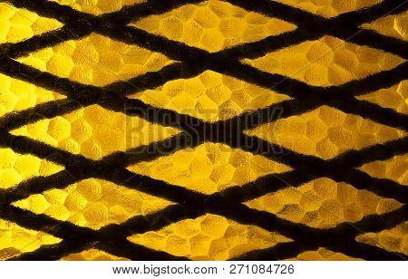 Geometrical Metal Grate And Yellow Decorative Glass From A Window Detail.