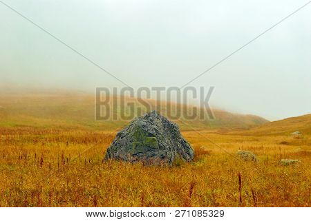 Huge Granite Boulder Lying In The Middle Of An Autumn Alpine Meadow On A Mountain Pass Sheltered By 