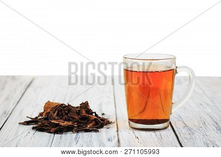 Cup Of Hot Black Tea And Dried Tea Leaves On Wooden Table With Place For Copyspace