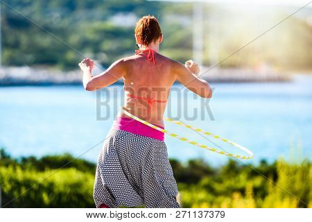 Attractive Adult Woman Is Playing With Hula Hoop In Nature.