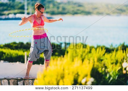 Attractive Adult Woman Is Playing With Hula Hoop In Nature.