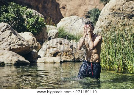 Young Man Splashing Water On Face. Refreshing In Wadi Shab, Sultanate Of Oman.
