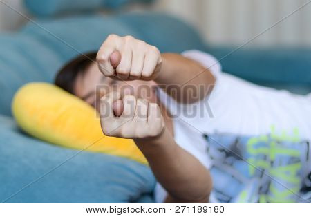 Teenager Boy Lying On Sofa At Home Showing Fig To Parents At Camera. Teen Rudeness And Protest. Rude