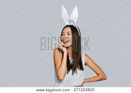 Cuter Than Any Bunny. Beautiful Young Asian Woman In Bunny Ears Smiling While Standing Against Grey 