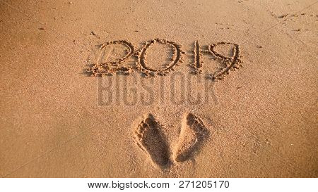 Closeup Photo Of 2019 New Year Numbers And Footrpints On Wet Sand At Ocean Beach. Concept Of New Yea